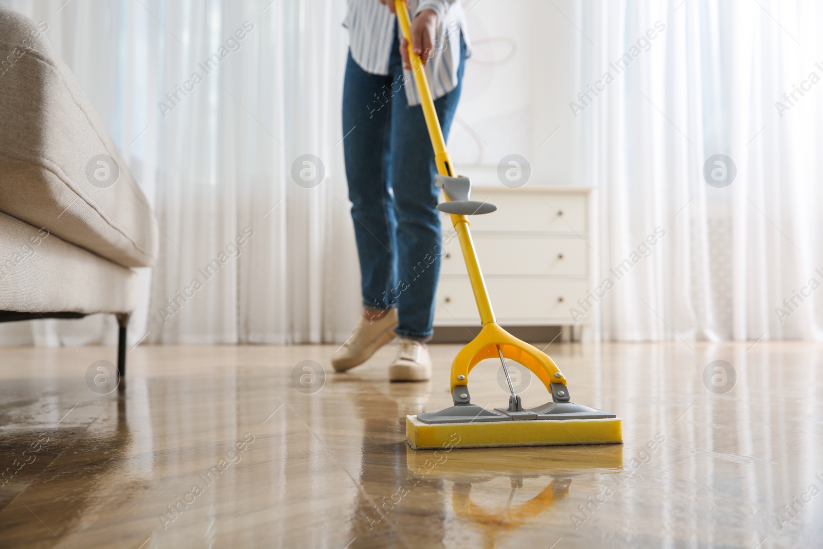 Photo of Woman cleaning parquet floor with mop indoors, closeup