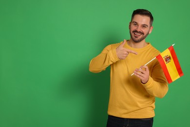 Man with flag of Spain on green background, space for text