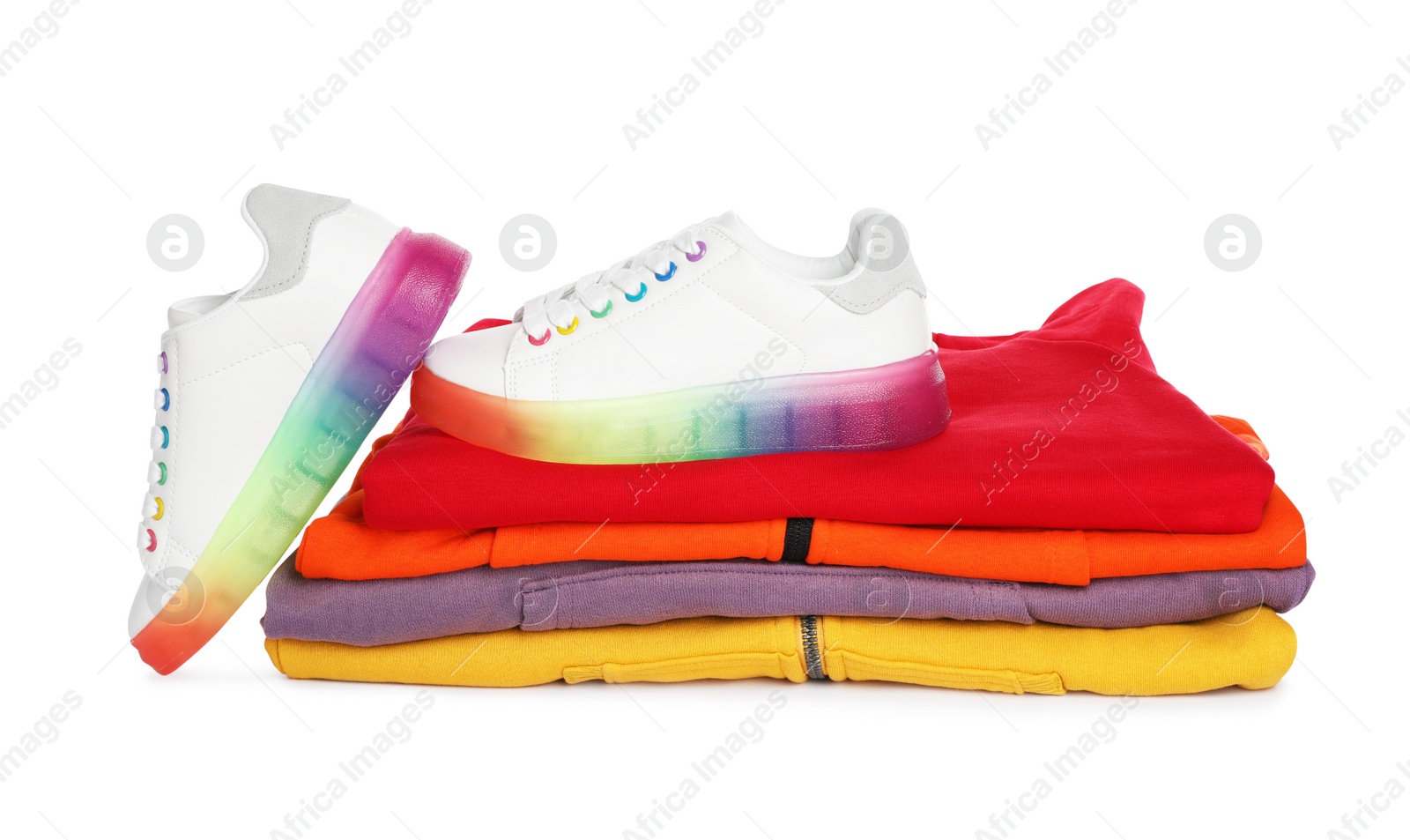 Photo of Stack of folded warm clothes and sport shoes on white background