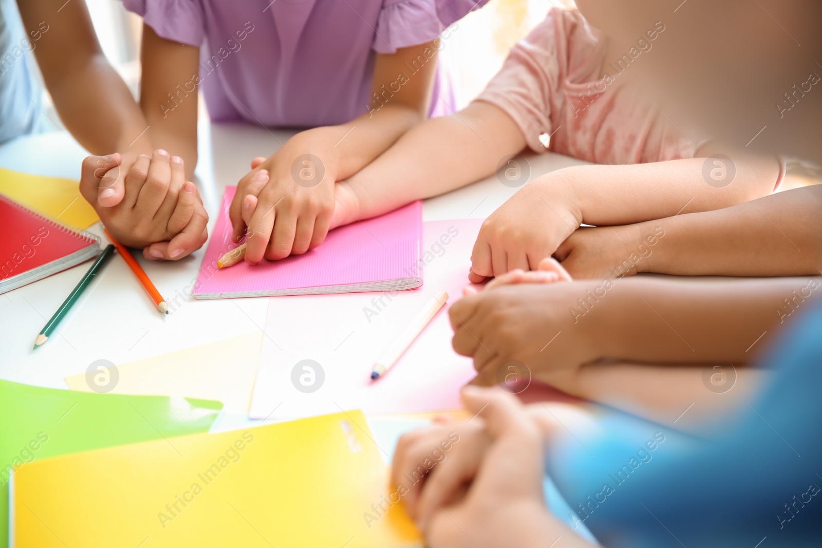 Photo of Little children holding hands at table, closeup. Unity concept