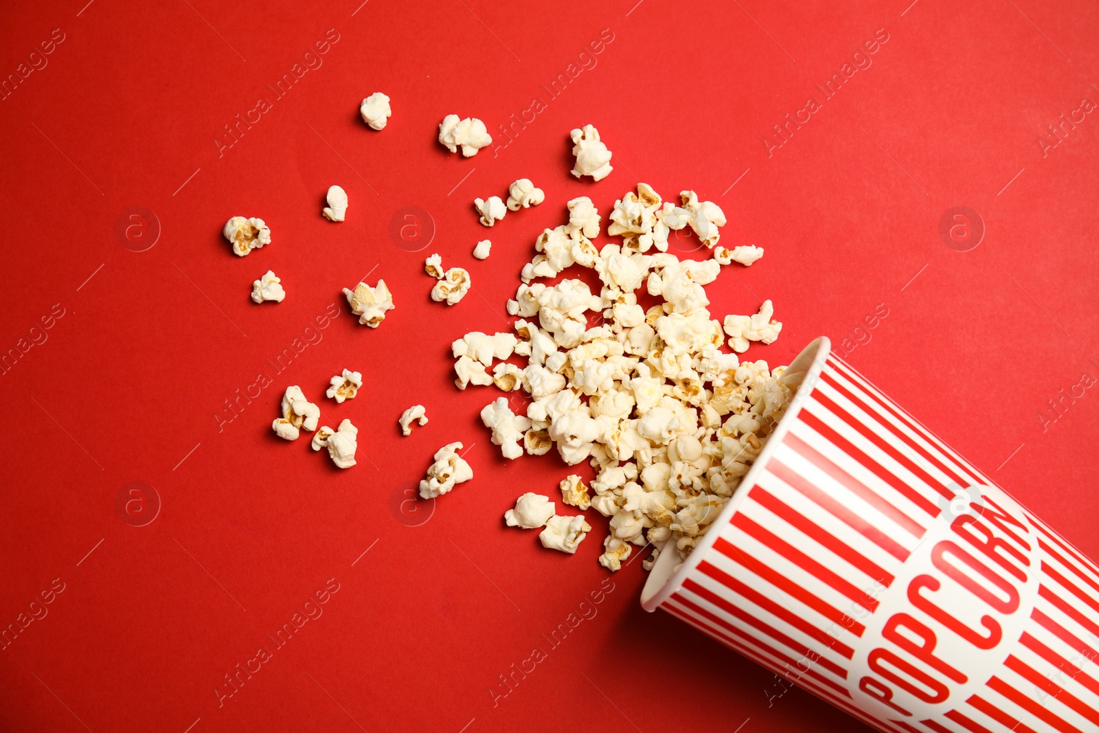 Photo of Paper cup with tasty fresh popcorn on color background, top view