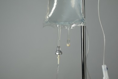 Photo of IV infusion set on pole against grey background, closeup. Space for text