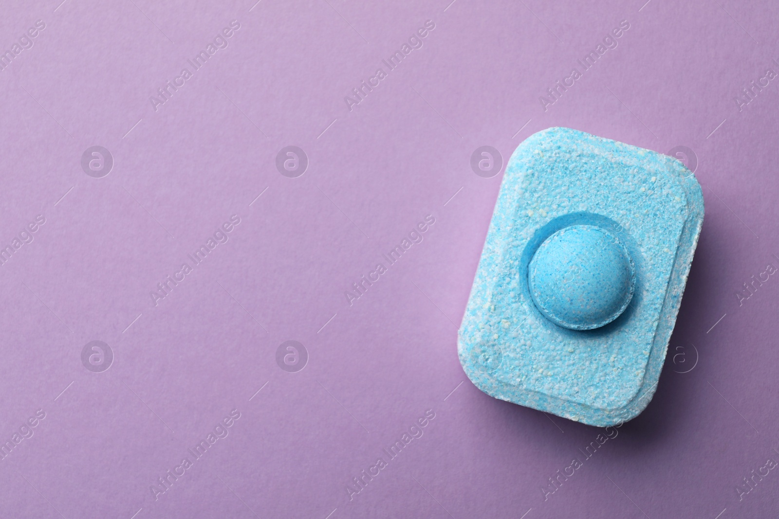 Photo of Water softener tablet on violet background, top view. Space for text