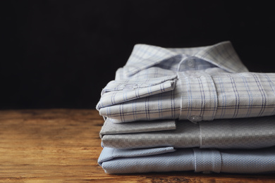 Photo of Stack of classic shirts on wooden table