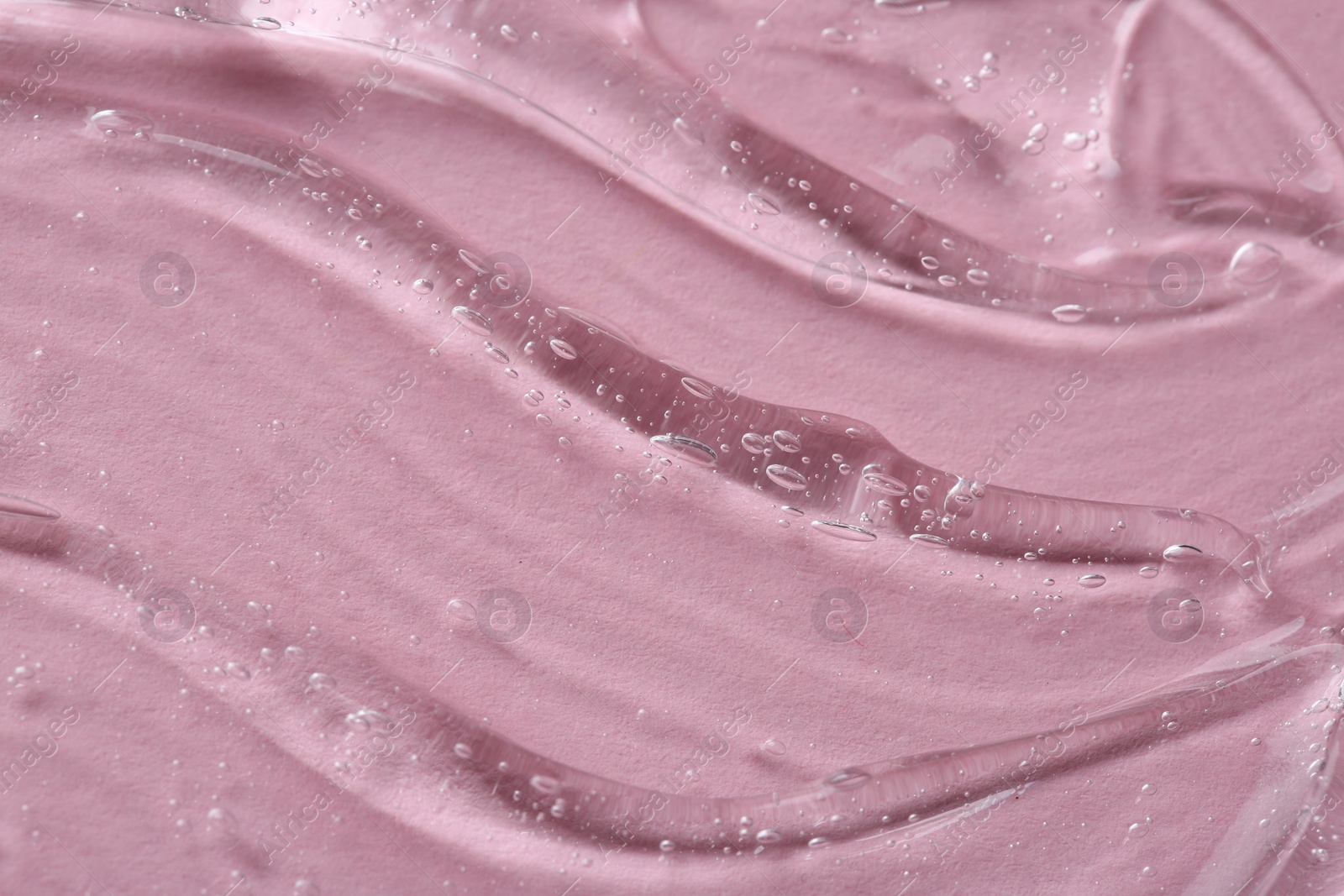 Photo of Clear cosmetic serum on pink background, macro view