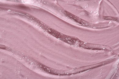 Clear cosmetic serum on pink background, macro view