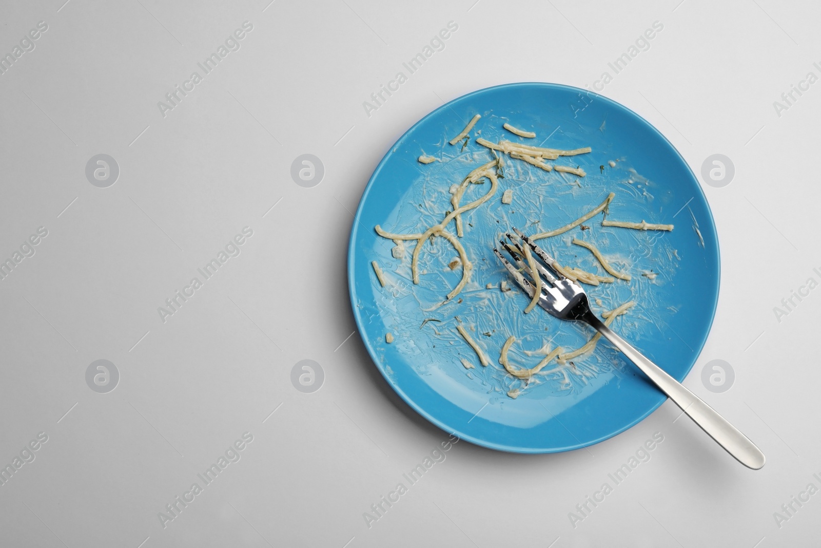 Photo of Dirty plate with food leftovers and fork on white background, top view