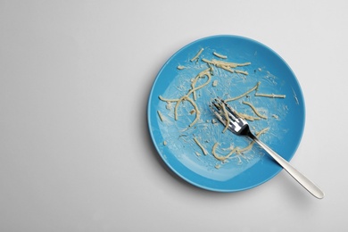 Photo of Dirty plate with food leftovers and fork on white background, top view