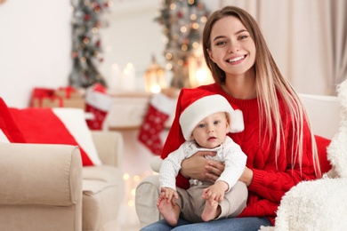 Happy mother with cute baby in room decorated for Christmas holiday