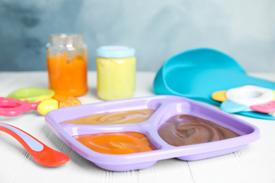 Photo of Healthy baby food and spoon on white wooden table