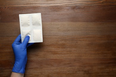 Man in glove with mustard plasters at wooden table, top view. Space for text