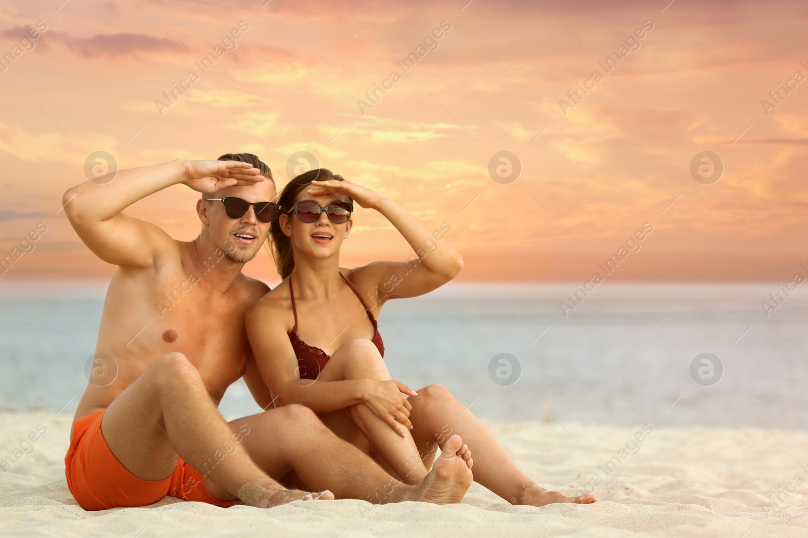 Photo of Young woman in bikini spending time with her boyfriend on beach. Lovely couple