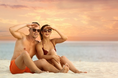 Young woman in bikini spending time with her boyfriend on beach. Lovely couple