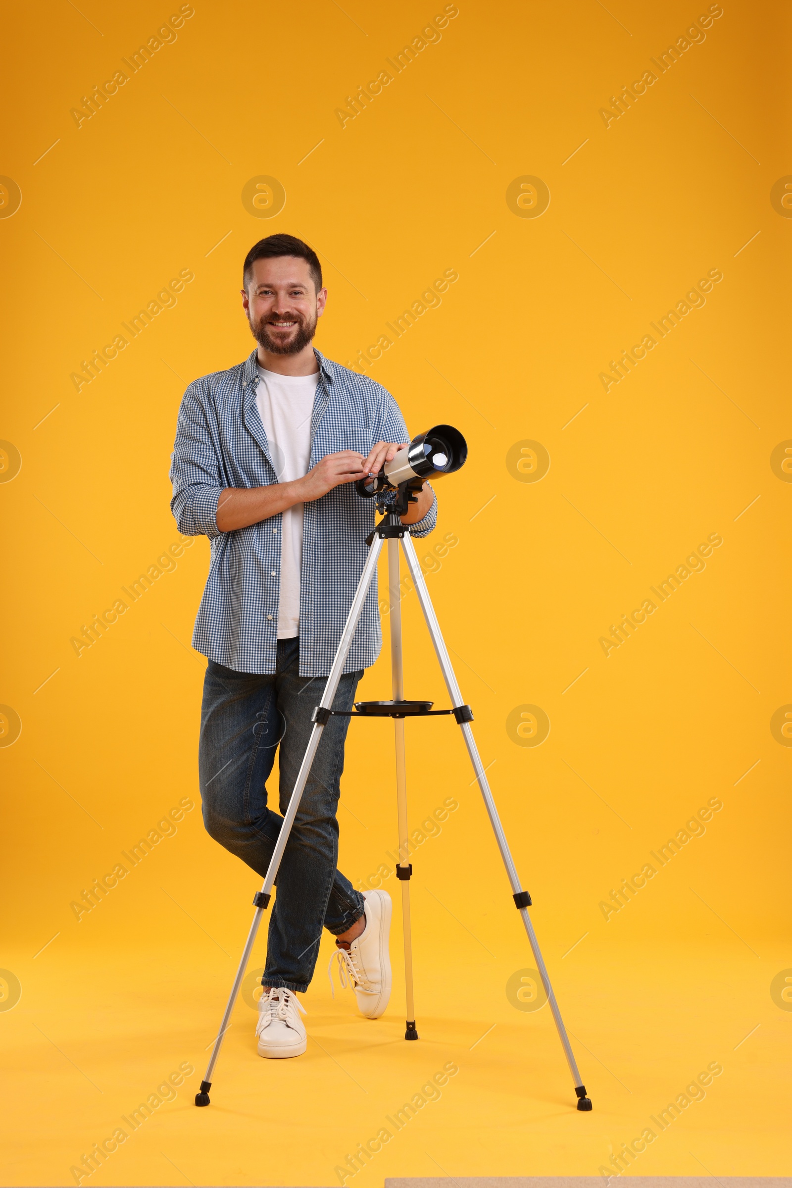 Photo of Happy astronomer with telescope on orange background