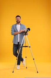 Happy astronomer with telescope on orange background