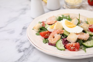 Photo of Delicious Caesar salad with shrimps on white marble table, closeup. Space for text