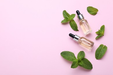 Photo of Bottles of essential oil and mint on pink background, flat lay. Space for text
