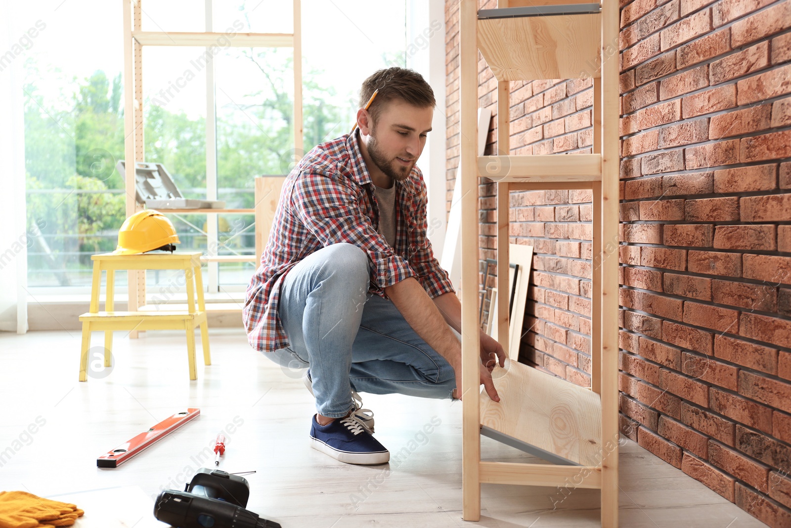 Photo of Young man working with shelving unit indoors