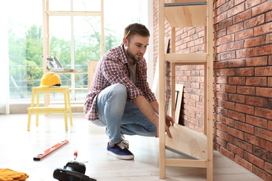 Photo of Young man working with shelving unit indoors