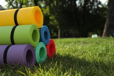 Photo of Bright exercise mats on fresh green grass outdoors, space for text