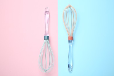 Two whisks on color background, top view