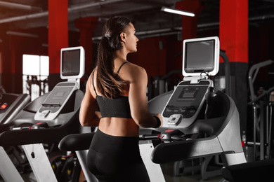 Photo of Young woman working out on treadmill in modern gym