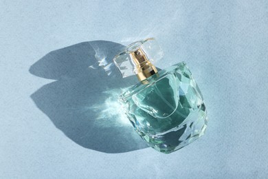 Photo of Luxury women's perfume. Sunlit glass bottle on grey background, top view. Space for text