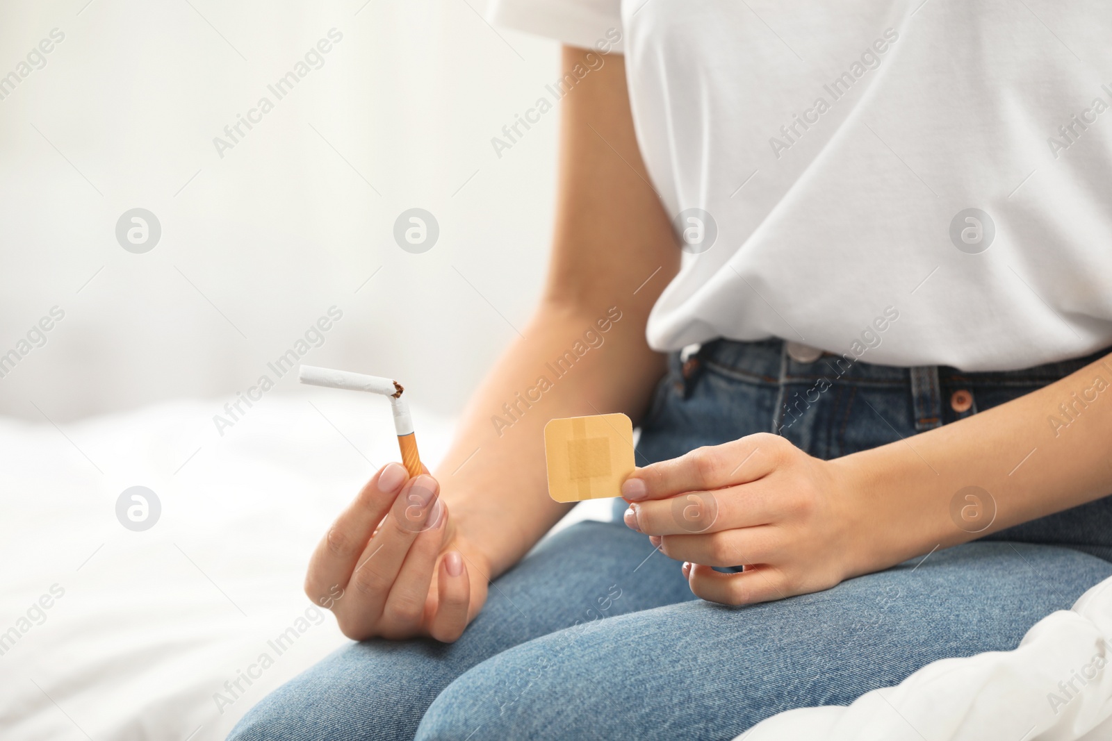 Photo of Young woman with nicotine patch and cigarette in bedroom, closeup