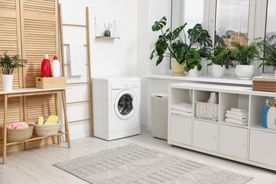 Photo of Laundry room interior with washing machine, houseplants and furniture