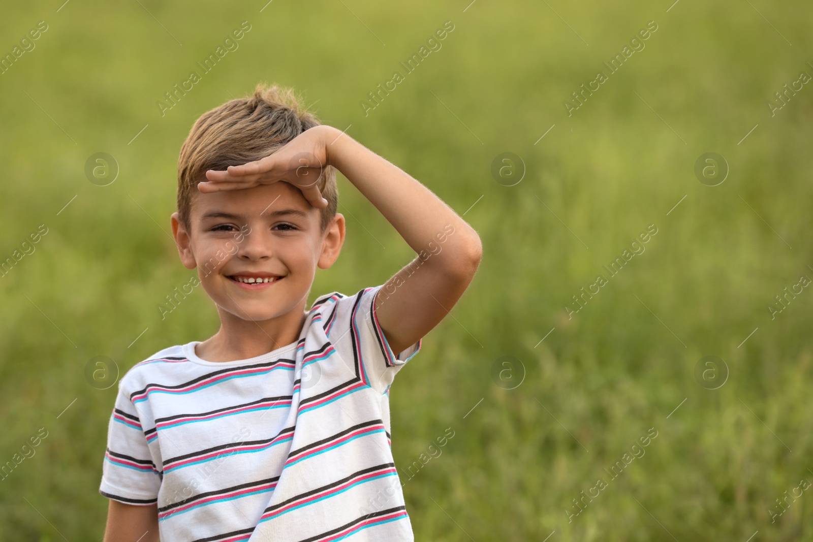 Photo of Cute little boy in field, space for text. Child spending time in nature