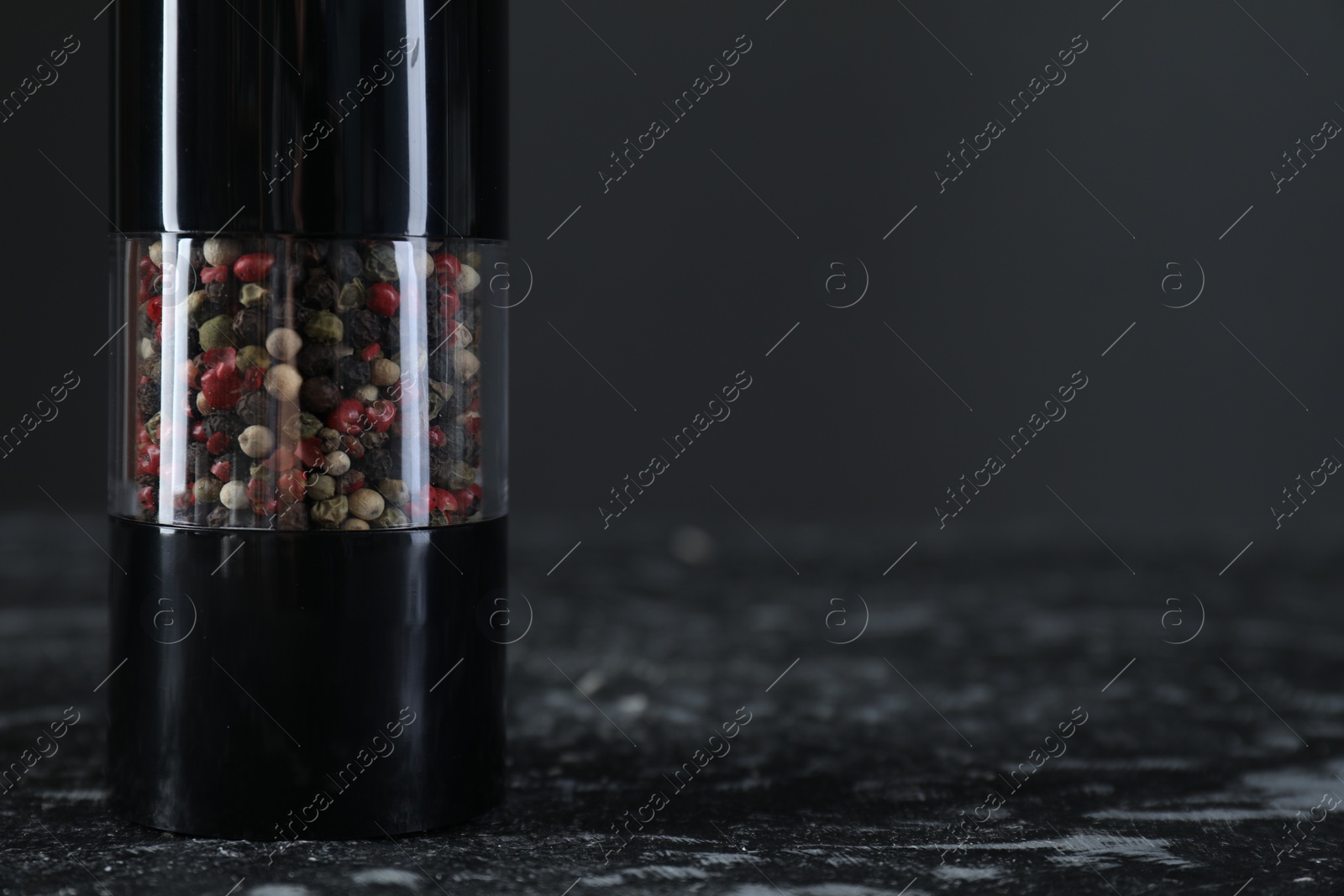 Photo of Pepper shaker on dark marble table, closeup. Space for text