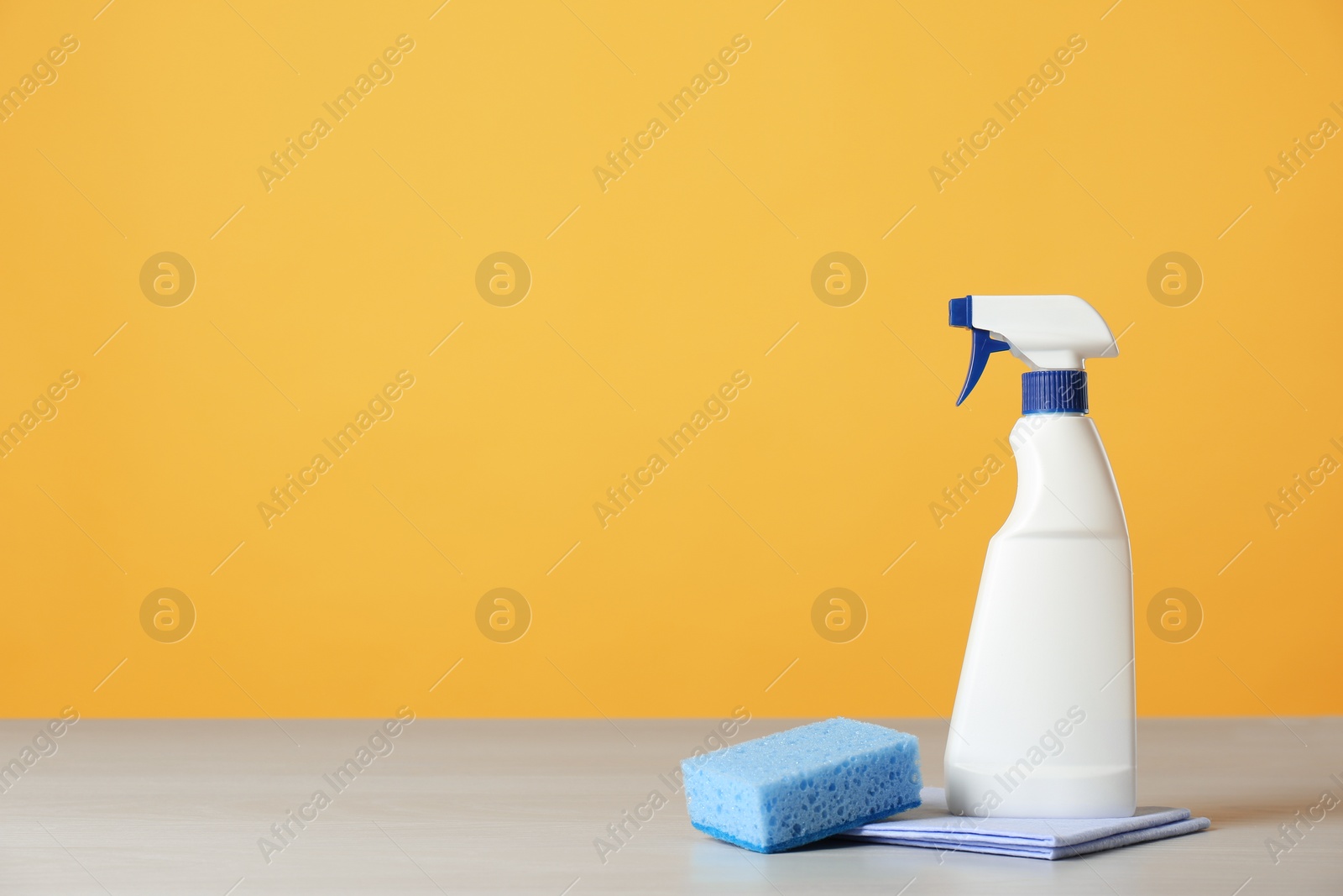 Photo of Bottle of cleaning product and supplies on light table. Space for text