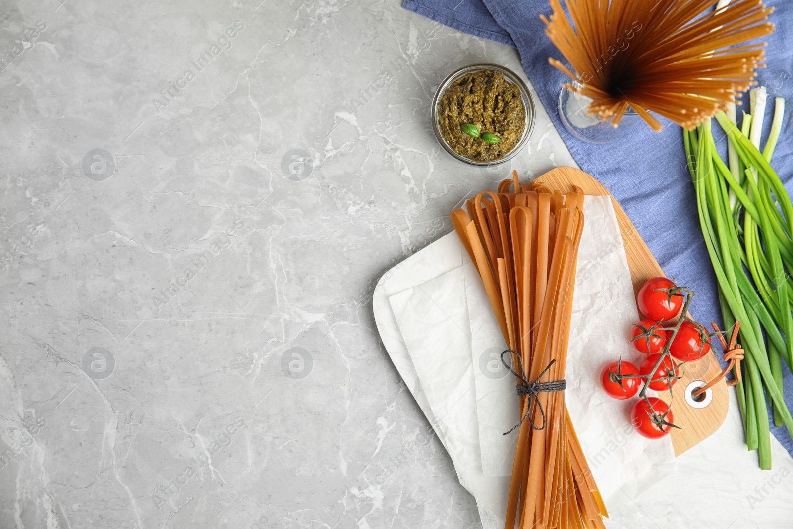 Photo of Flat lay composition with uncooked buckwheat noodles on light grey table. Space for text