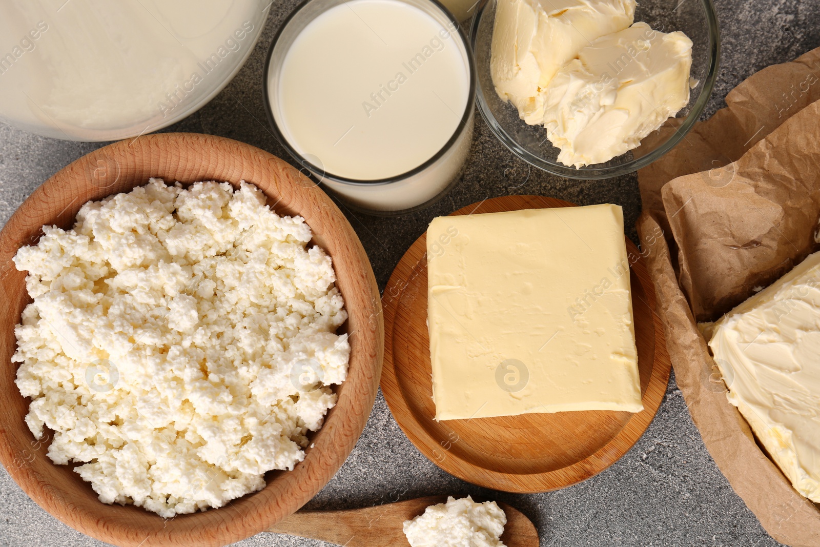 Photo of Tasty homemade butter and dairy products on grey table, flat lay