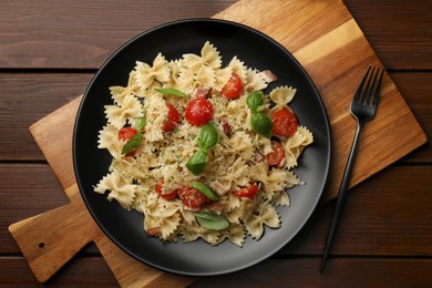 Delicious pasta with tomatoes, basil and parmesan cheese on wooden table, top view