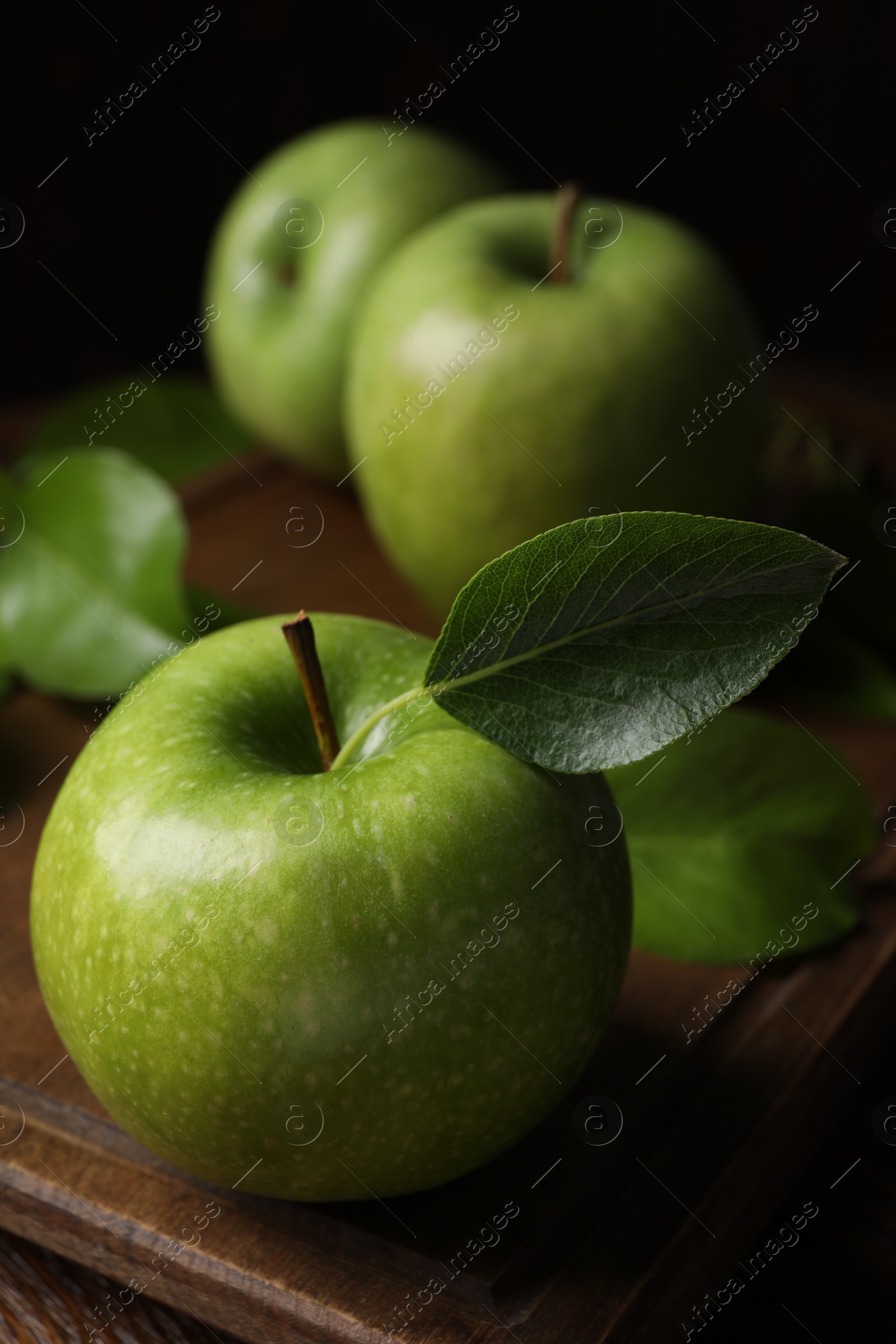 Photo of Fresh ripe green apples with leaves on wooden table, closeup