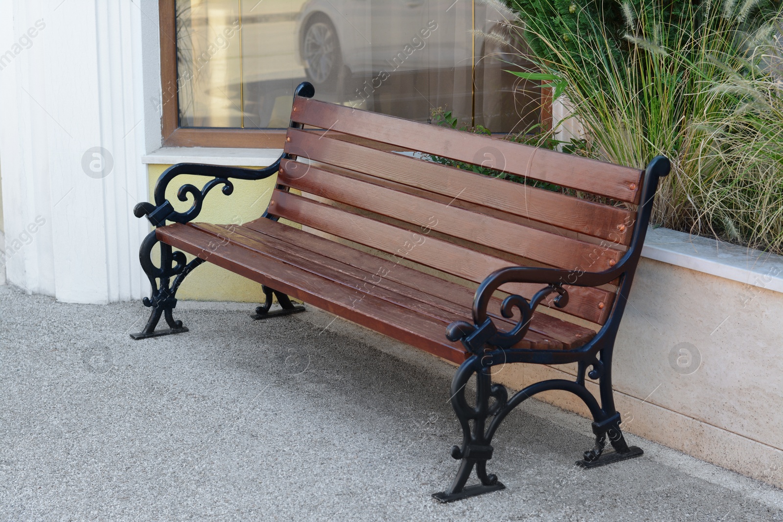 Photo of Beautiful wooden bench with wrought armrests on city street