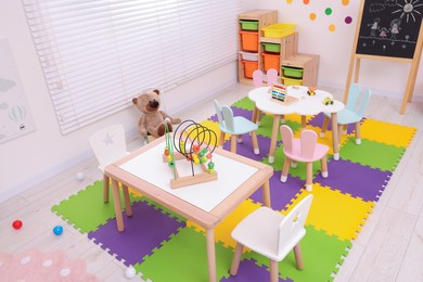 Photo of Stylish kindergarten interior with toys and modern furniture, above view