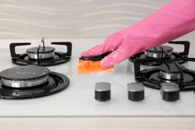 Photo of Person cleaning gas stove with sponge, closeup