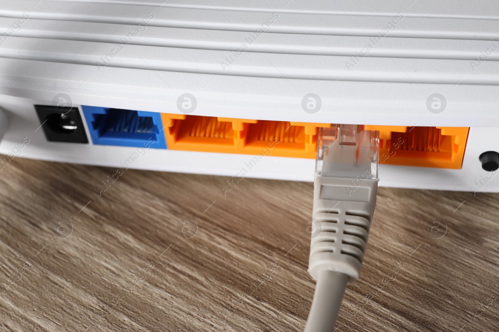 Photo of Connected cable to router on wooden table, closeup. Wireless internet communication