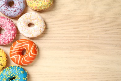 Delicious glazed donuts on wooden table, flat lay. Space for text