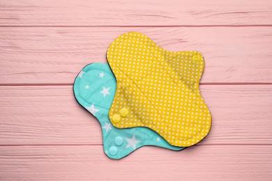 Photo of Reusable cloth menstrual pads on pink wooden table, flat lay