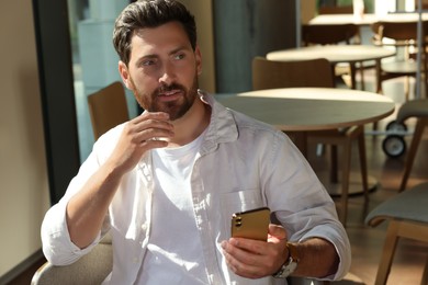 Photo of Handsome man using his smartphone in cafe