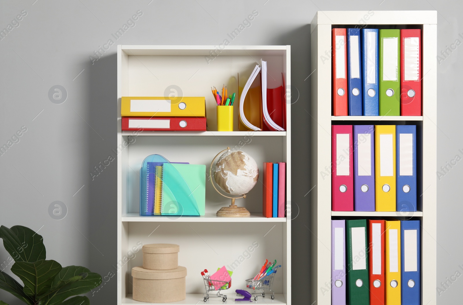 Photo of Colorful binder office folders and other stationery on shelving unit indoors