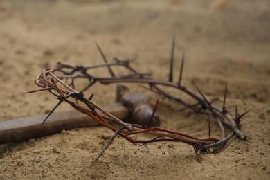 Photo of Crown of thorns and hammer on sand. Easter attributes