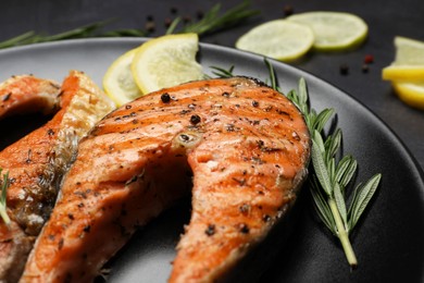 Photo of Plate with tasty salmon steaks on black table, closeup