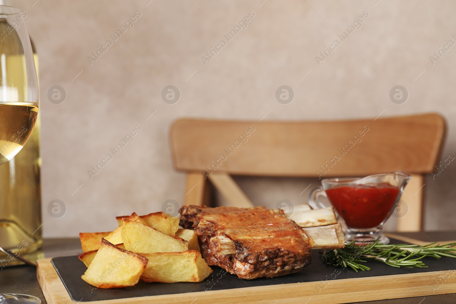 Photo of Fried ribs served with garnish, sauce and wine on table, space for text. Delicious meat