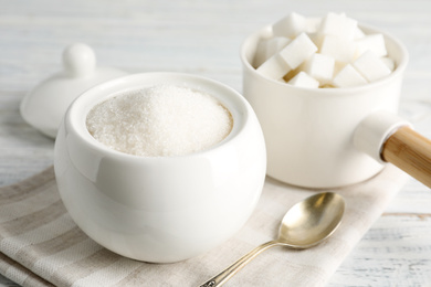 Photo of Dishware with sugar on white wooden table