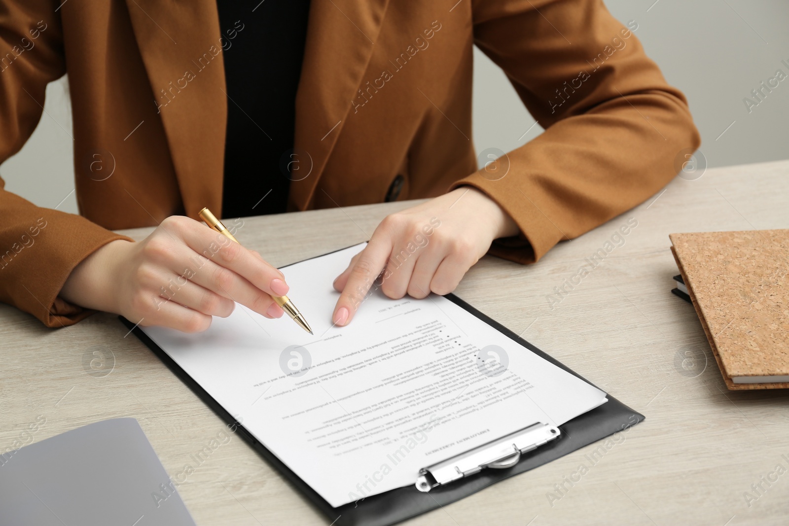 Photo of Woman signing document at wooden table, closeup