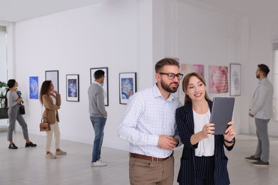 Photo of Happy couple with tablet at exhibition in art gallery